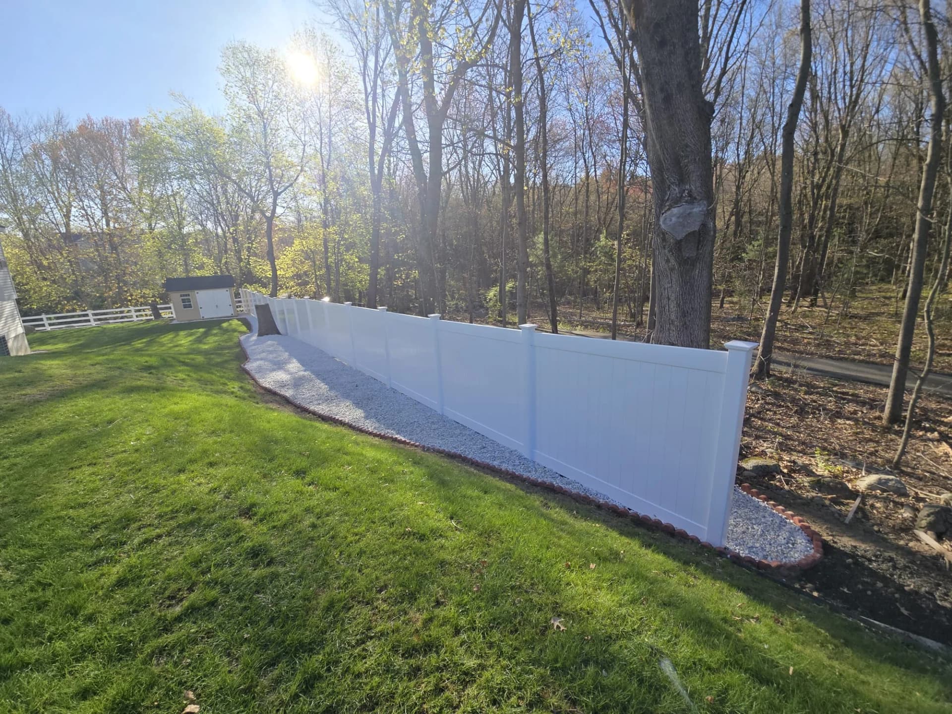 White privacy fence following the edge of a residential lawn in Shrewsbury, MA