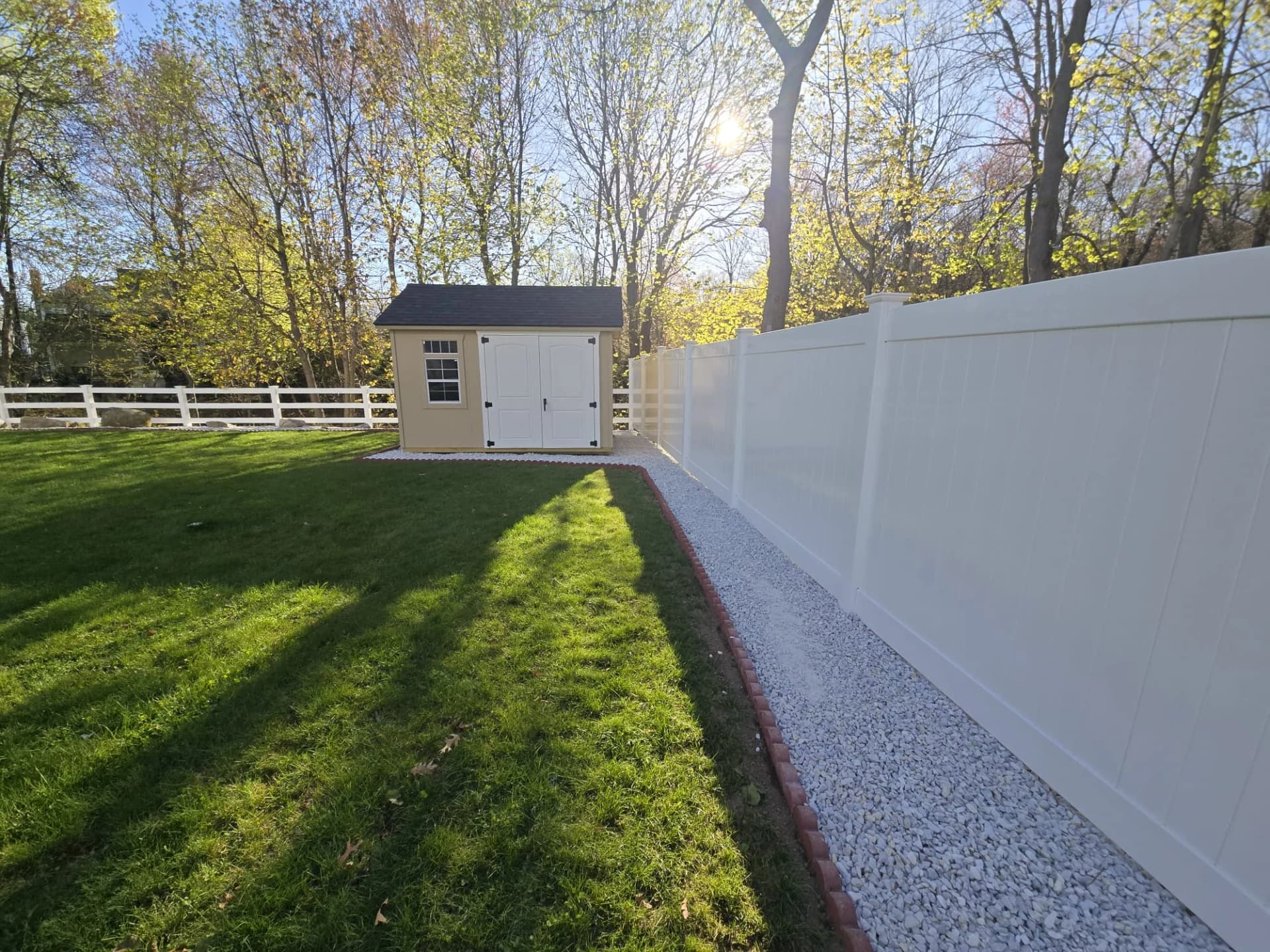 Closer view of white privacy fence panels beside a gravel border in Shrewsbury, MA